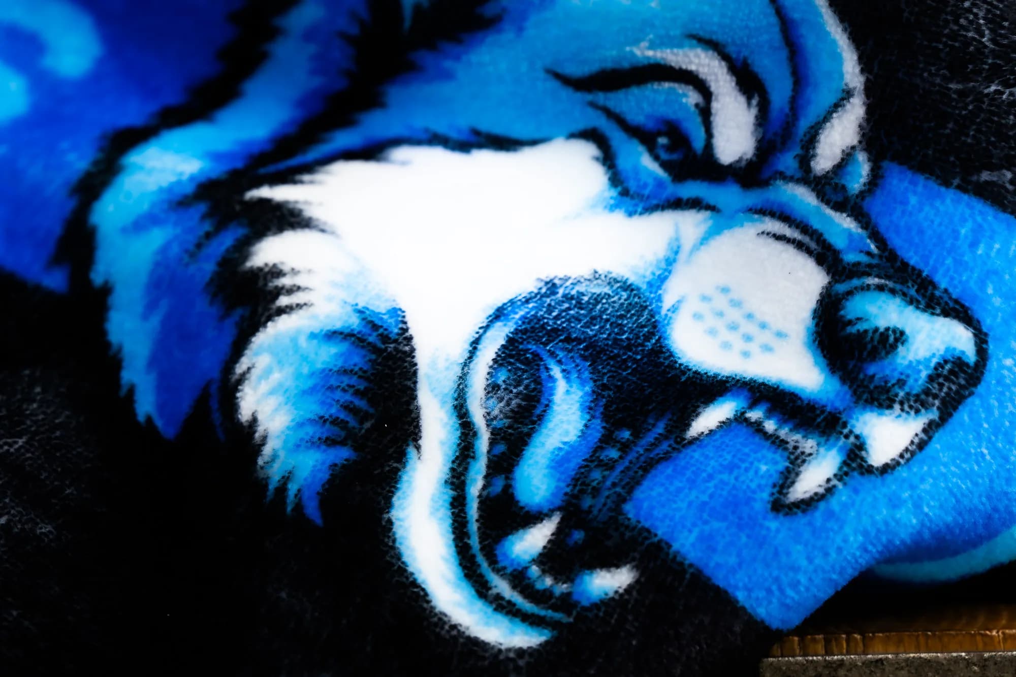 Macro close-up of dense NubaySoft plush and the stitched satin binding on a custom printed blanket